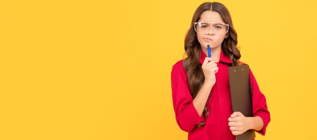 Niña pensativa en anteojos sostiene concentración de carpeta de papel Constructor de niños con gafas protectoras diseño de cartel horizontal Espacio de copia de encabezado de banner