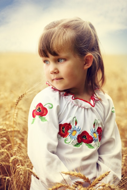 Niña pensativa en un campo de trigo