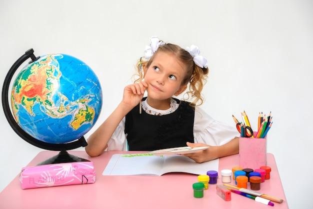 Niña pensativa dibuja en la escuela