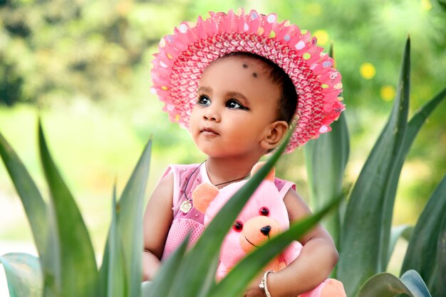 Foto niña pensativa con sombrero mientras está sentada en medio de las hojas