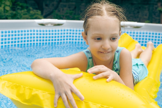 Niña pequeña acostada en el flotador de la piscina