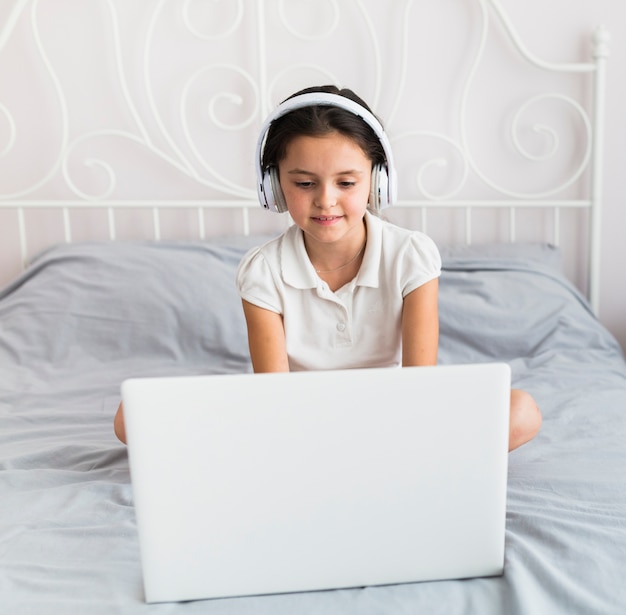 Foto niña pequeña adorable usando su ordenador portátil