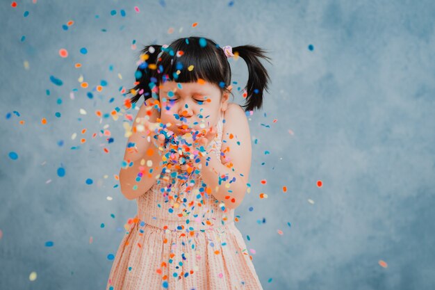 Niña pequeña alegremente arroja coloridos guirnaldas y confeti.