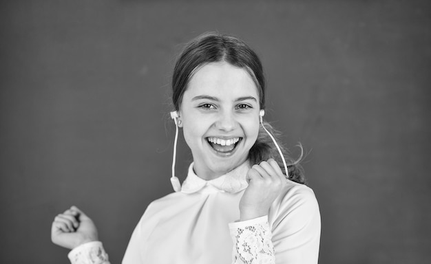 Niña pequeña en auriculares en la pizarra escuchando audiolibros ebook gratis chica genial en auriculares escuchando música concepto de aprendizaje electrónico educación en el hogar educación en línea regreso a la escuela disfrutar de una nueva canción