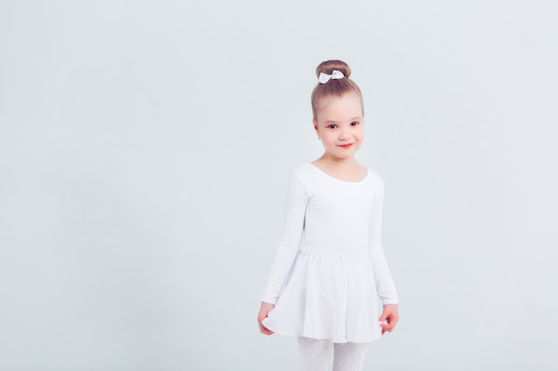 Niña pequeña bailar ballet en fondo blanco Retrato de pequeña bailarina sonriendo