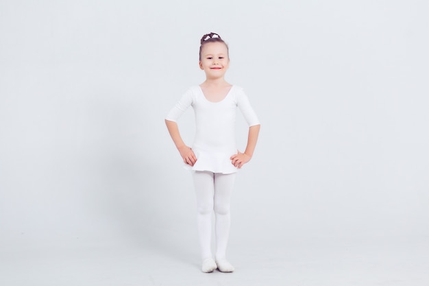 Niña pequeña bailar ballet en fondo blanco Retrato de pequeña bailarina sonriendo