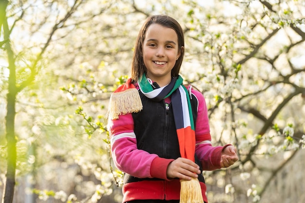 Niña pequeña con la bandera de los emiratos, úsela para el Día de la Independencia de los Emiratos el 2 de diciembre