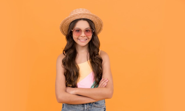 Niña pequeña belleza usa sombrero de paja y gafas niña alegre sobre fondo naranja