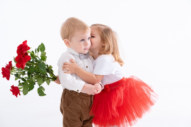 Niña pequeña besando a niño en el día de San Valentín sobre fondo blanco.