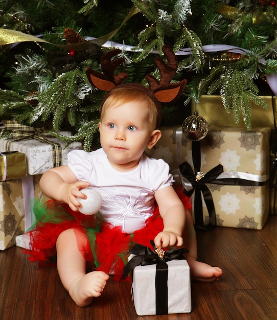 Niña pequeña con la caja de regalos cerca Decorando el árbol de Navidad Feliz momento