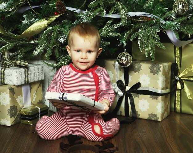 Niña pequeña con la caja de regalos cerca Decorando el árbol de Navidad Feliz momento