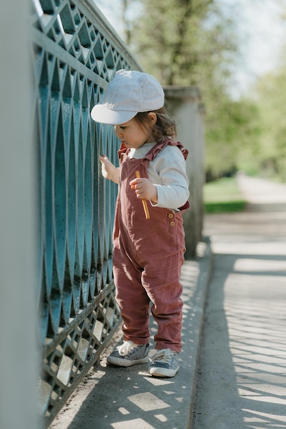 Una niña pequeña camina cerca de la cerca del puente del jardín