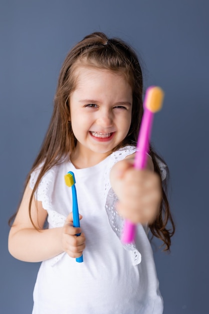 Una niña pequeña con un cepillo de dientes en la mano sostiene un cepillo de dientes.