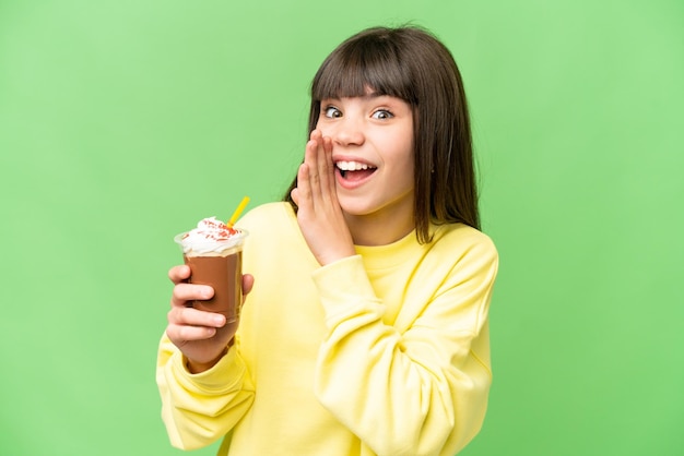 Niña pequeña con crema de chocolate sobre fondo de clave de croma aislado susurrando algo