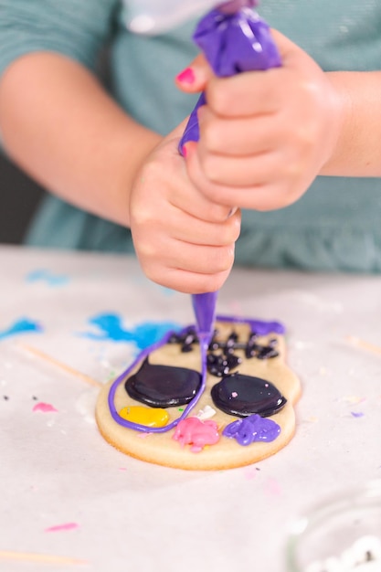 Niña pequeña decorando galletas de azúcar con glaseado real para la festividad del Día de los Muertos.