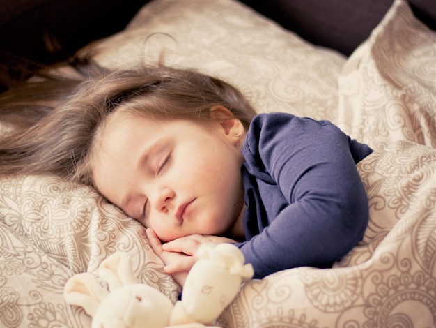 una niña pequeña durmiendo con un conejo conejo en su regazo