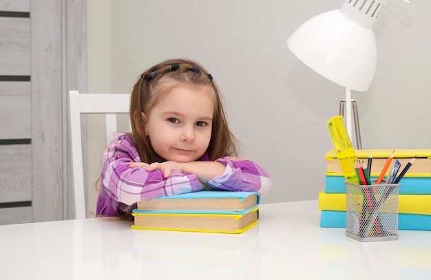 Niña pequeña y encantadora está mintiendo sobre libros. hace la tarea escolar en casa. Enfoque selectivo.