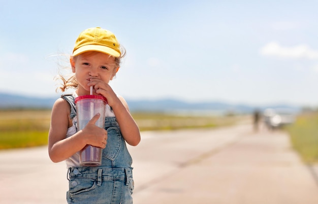 Una niña pequeña está bebiendo de un tubo de un vaso enorme.