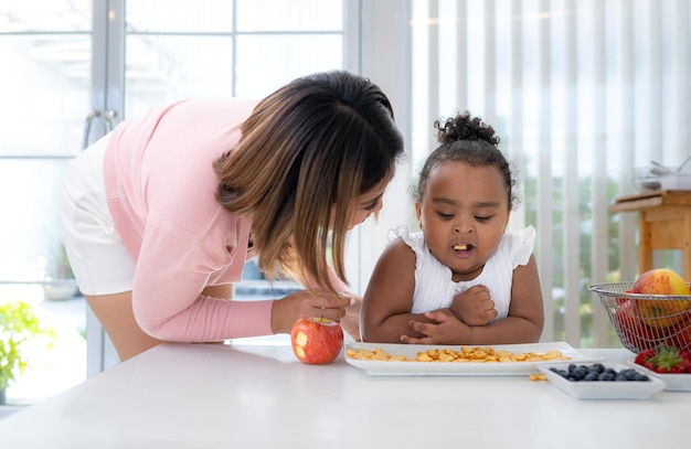 Una niña pequeña está comiendo galletas en la mesa que su madre le trajo como bocadillo