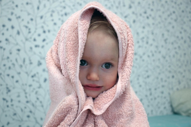 Una niña pequeña está envuelta en una toalla después de bañarse retrato en primer plano