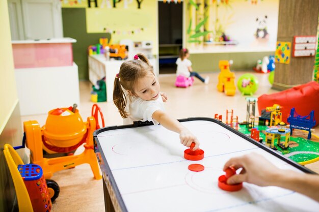 Una niña pequeña está jugando en el centro creativo para niños jugando hockey de aire.