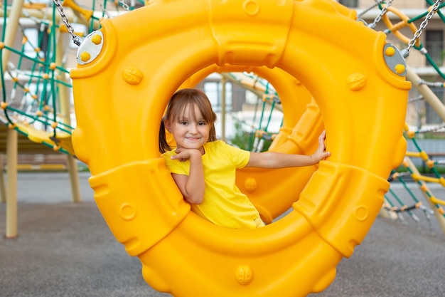 Una niña pequeña está jugando en un parque infantil moderno en el patio de un nuevo complejo residencial