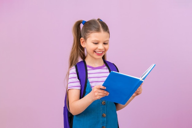 Una niña pequeña está leyendo un libro interesante Un niño está estudiando una enciclopedia El niño tiene un libro de texto en sus manos y sonríe