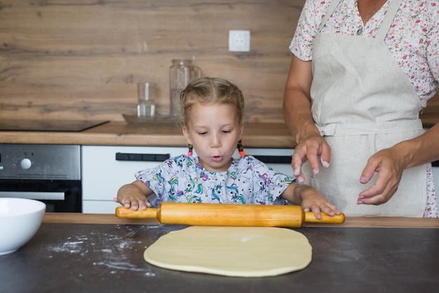 Una niña pequeña estira la masa con su madre Preparación de la masa