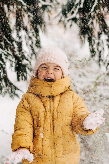 Niña pequeña feliz con día de nieve en invierno