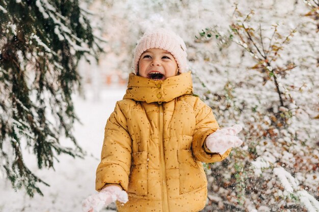 Niña pequeña feliz con día de nieve en invierno