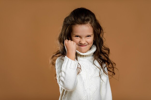 Niña pequeña gritando enojada con suéter blanco