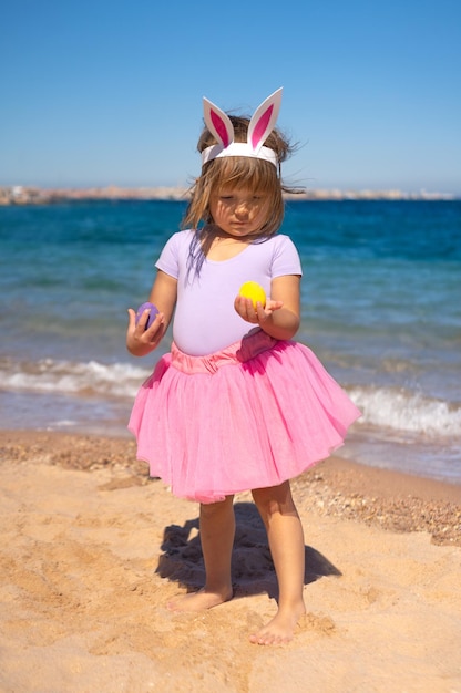 Niña pequeña con huevos de pascua en la playa