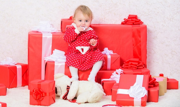 Niña pequeña juega cerca de una pila de cajas de regalo Vacaciones familiares Cosas que hacer con niños pequeños en Navidad Regalos de Navidad para niños pequeños Celebrar la primera Navidad Regalos para niños Primera Navidad