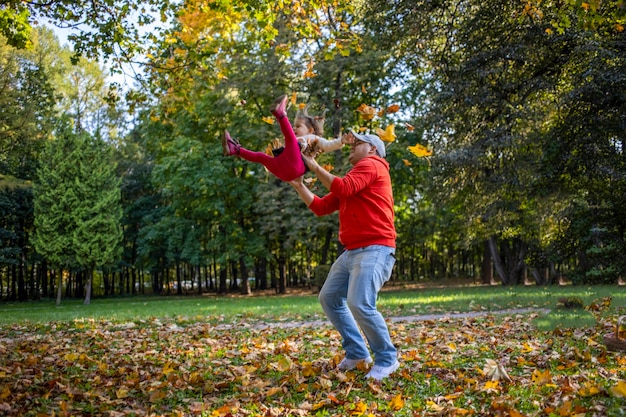 Niña pequeña juega con el padre al aire libre en el parque de otoño