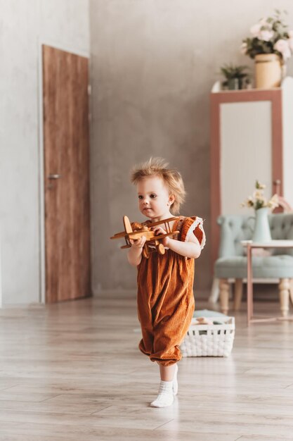 Niña pequeña jugando con un avión de madera de juguete en el interior