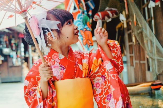 Foto una niña pequeña con un kimono rojo