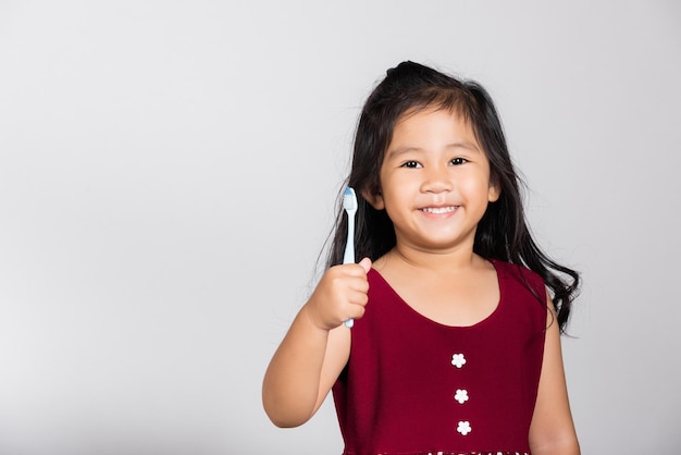 Niña pequeña y linda de 3 años muestra los dientes cepillados y sonríe