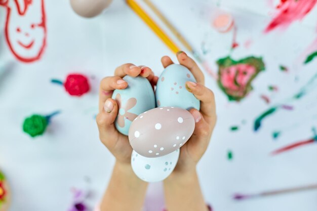 Una niña pequeña y linda el día de Pascua sostiene un huevo de Pascua en la mano