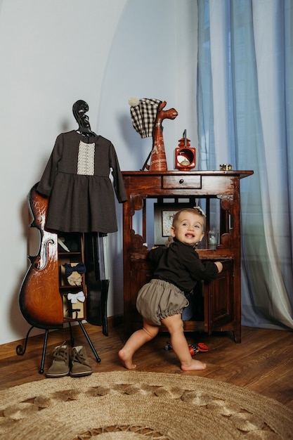 Niña pequeña linda en ropa vintage jugando en casa moda de bebé de género neutral unisex