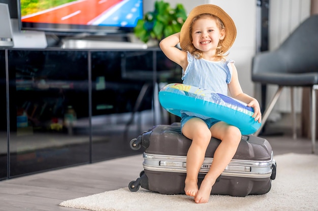 Niña pequeña con maleta equipaje y salvavidas inflable lista para viajar de vacaciones