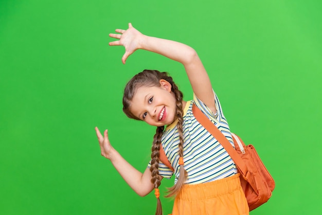 Una niña pequeña con un maletín está jugando mucho. Fondo verde aislado.