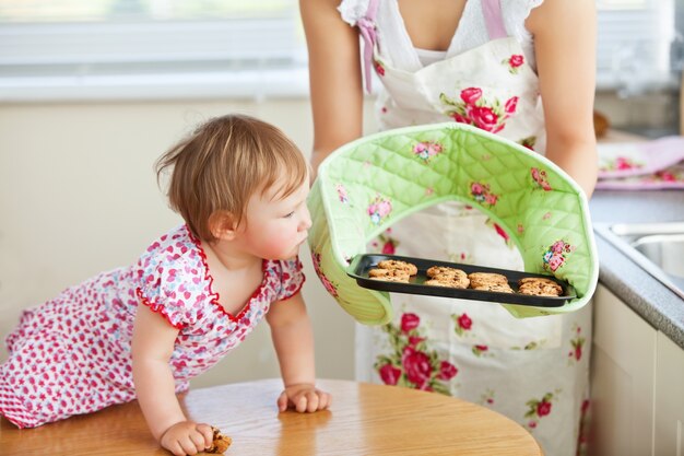 Niña pequeña mirando galletas en la cocina