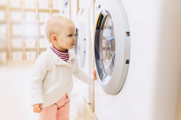 Niña pequeña mirando una lavadora