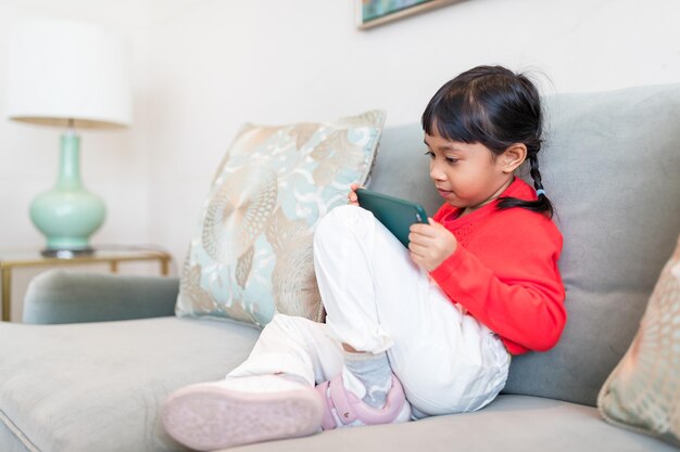 Niña pequeña mirando el teléfono celular en casa