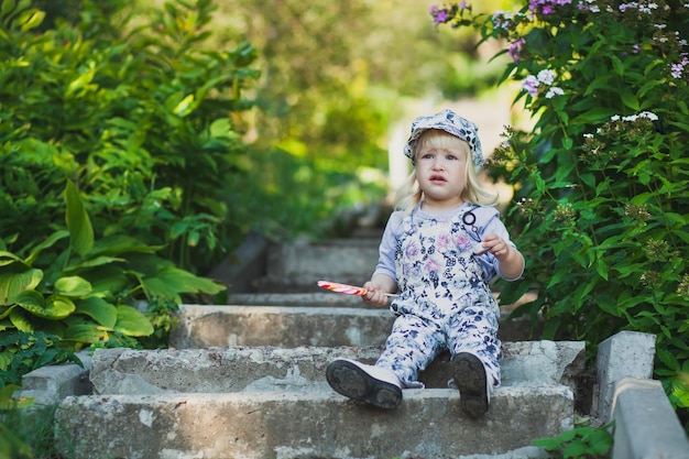 Niña pequeña molesta con piruleta de colores en un paseo de verano