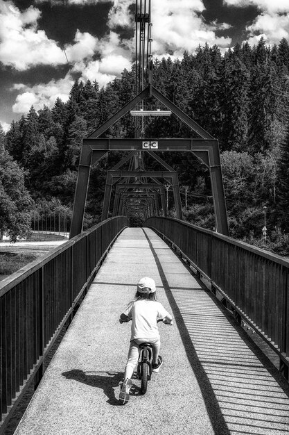 Niña pequeña montando en bicicleta en el puente para peatones