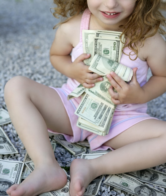 Foto niña pequeña con muchos billetes de dólar