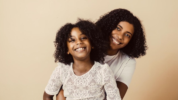 Niña pequeña y mujer negra joven juntos mirando a la cámara madre e hijas abrazándose