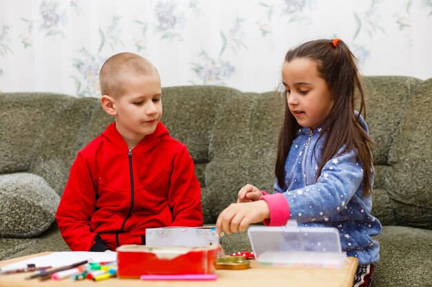 La niña pequeña y el niño concentrado trabajan juntos. niño y niña aprenden y juegan juntos en la mesa. Los niños disfrutan escribiendo a mano. Amistad