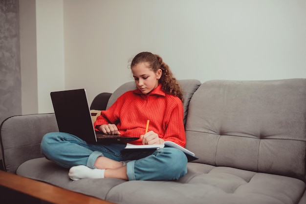 Una niña pequeña, un niño en edad preescolar, usa una computadora portátil para estudiar en casa, el niño sonríe felizmente y recibe conocimiento de forma remota, concepto digital de aprendizaje electrónico, aprendizaje electrónico a distancia